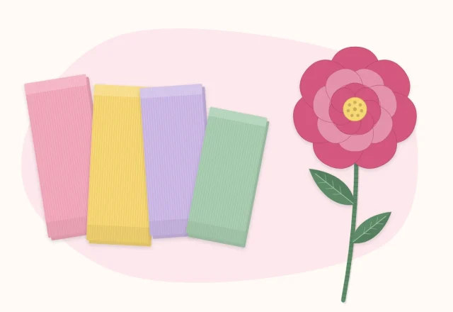 Folds of crepe paper in several colors beside one finished crepe paper flower