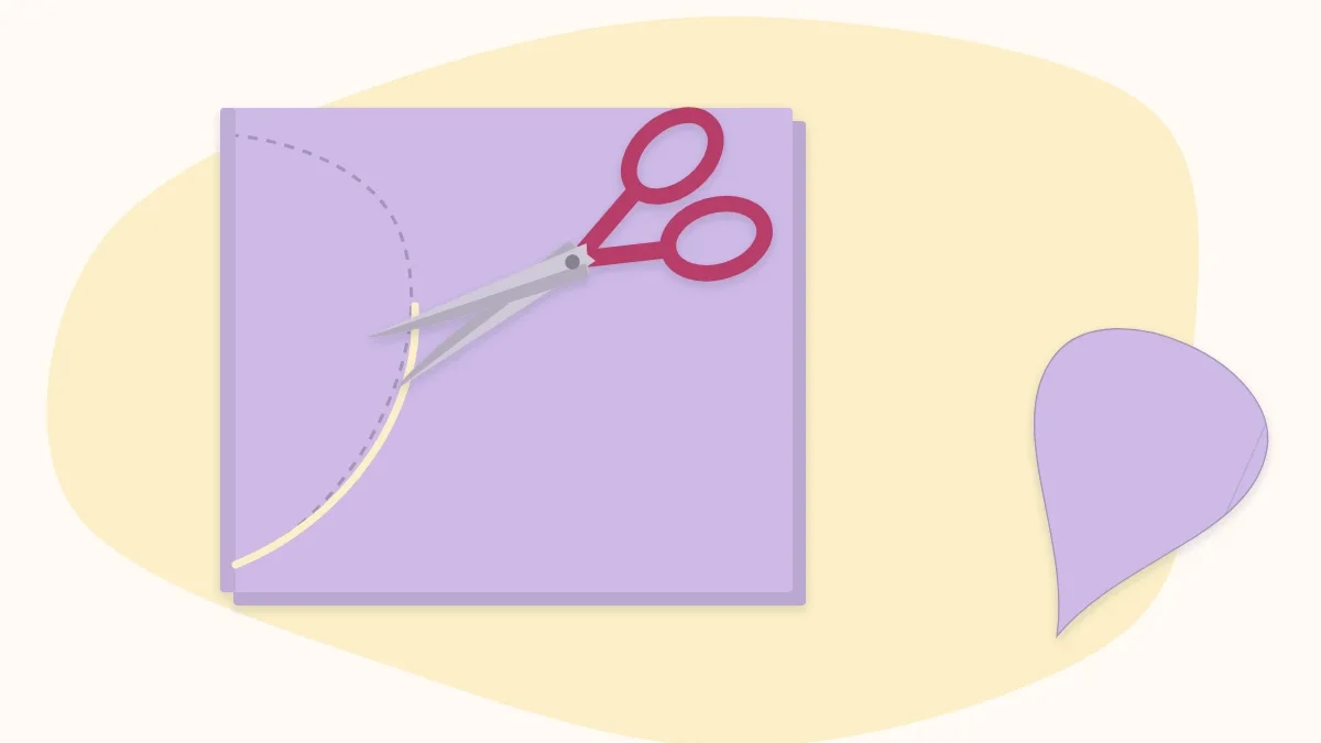 Scissors cutting a petal shape from a folded piece of pink paper