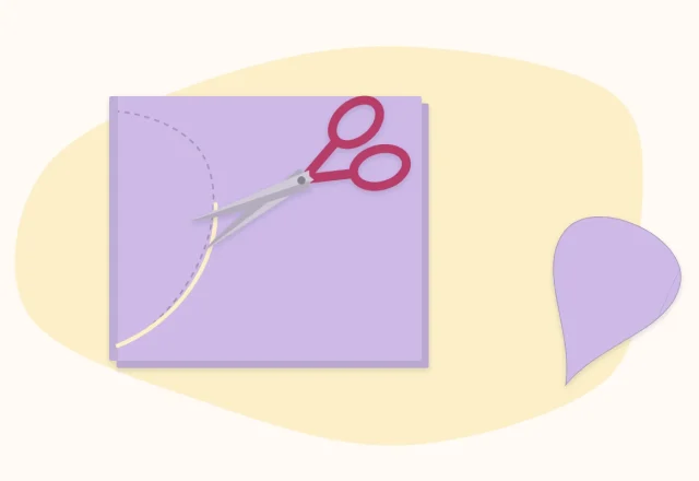 Scissors cutting a petal shape from a folded piece of pink paper