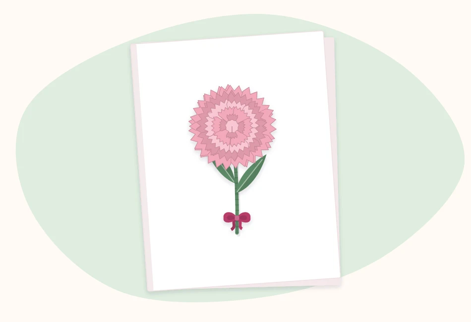A blank folded card with a small pink paper carnation, green stem and leaves attached to the front