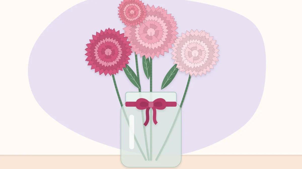 Pink and white paper carnations in a small glass jar tied with a ribbon