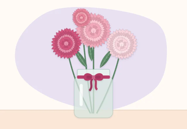 Pink and white paper carnations in a small glass jar tied with a ribbon