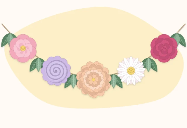 A paper flower garland draped in a gentle curve with green leaves between the flowers