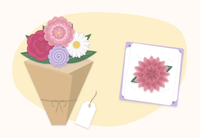 A small paper flower bouquet with a blank gift tag beside a single paper flower in a box