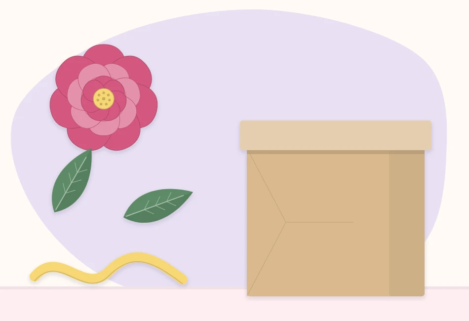 A flat-backed paper flower, two green paper leaves and a length of ribbon beside a plain wrapped gift box
