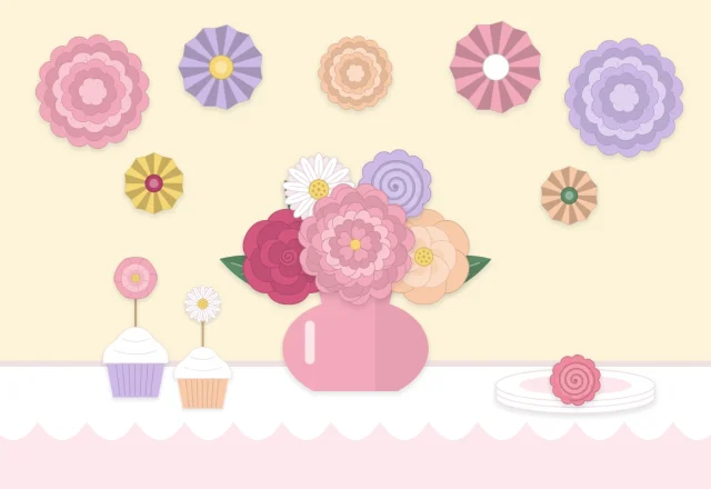 Party table with a paper flower centerpiece and a cluster of paper flowers on the wall behind it