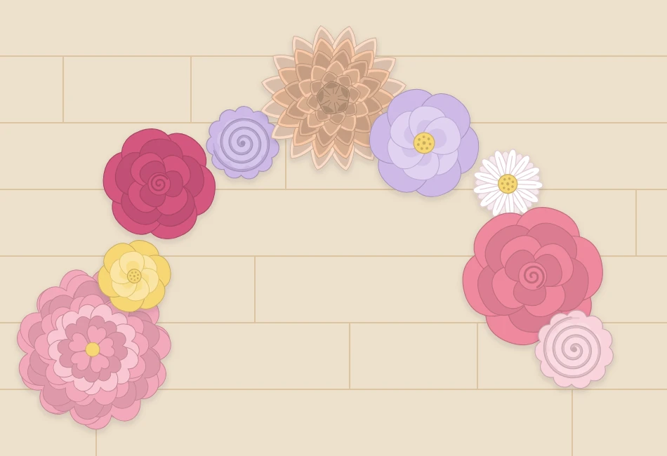 Paper flowers in three sizes laid out on the floor in a loose crescent shape before being hung on a wall