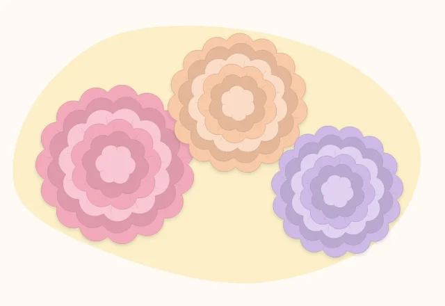 Three fluffy tissue paper pom flowers in pink, peach and lilac